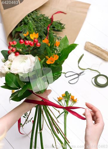 Image of Female florist making beautiful bouquet at flower shop