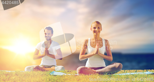 Image of happy couple making yoga and meditating outdoors