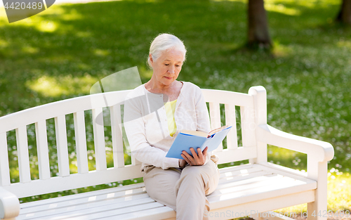 Image of senior woman reading book at summer park