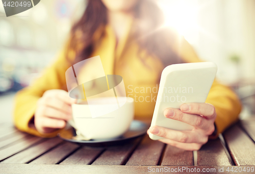 Image of close up of woman texting on smartphone at cafe