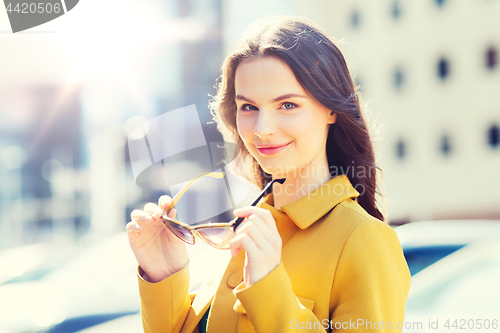 Image of smiling young woman with sunglasses in city