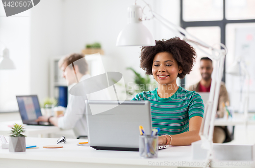 Image of happy african woman with laptop computer at office