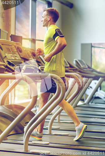 Image of man with smartphone exercising on treadmill in gym