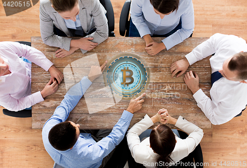 Image of business team at table with bitcoin icon