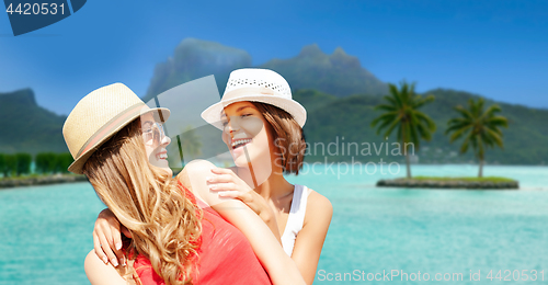 Image of smiling young women in hats on bora bora beach