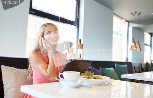 Image of happy young woman with tablet pc at restaurant