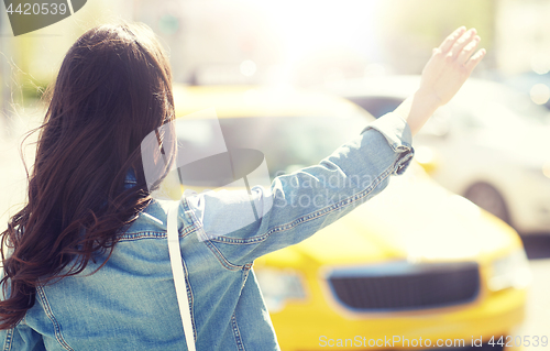 Image of young woman or girl catching taxi on city street