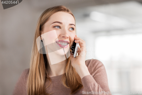 Image of businesswoman calling on smartphone at office