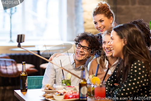 Image of friends taking selfie by smartphone at bar or cafe