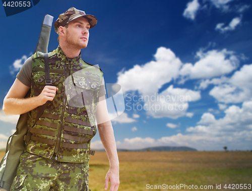 Image of young soldier or hunter with gun over savannah