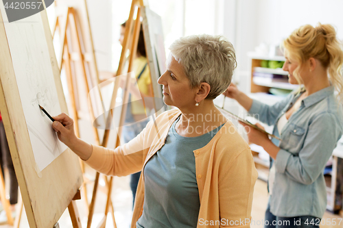 Image of senior woman drawing on easel at art school studio