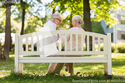 Image of happy senior couple sitting on bench at park