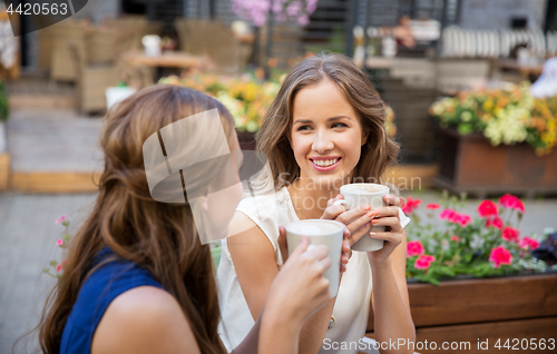Image of happy young women drinking coffee at outdoor cafe