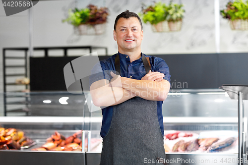 Image of male seller with seafood at fish shop fridge