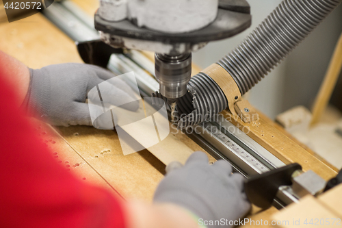 Image of carpenter with drill press and board at workshop