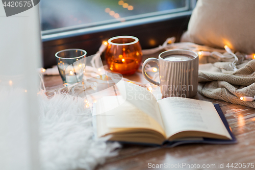 Image of book and coffee or hot cchocolate on window sill