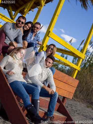 Image of Group of friends having fun on autumn day at beach