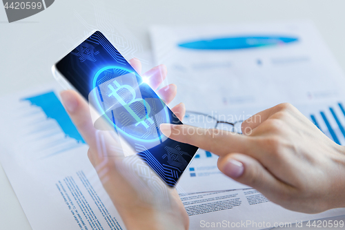 Image of close up of hand with bitcoin on smartphone screen