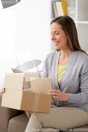 Image of smiling woman opening parcel box at home