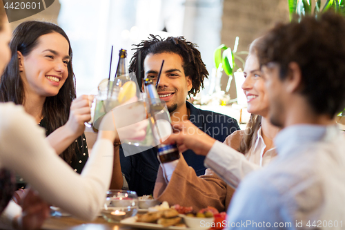 Image of happy friends clinking drinks at bar