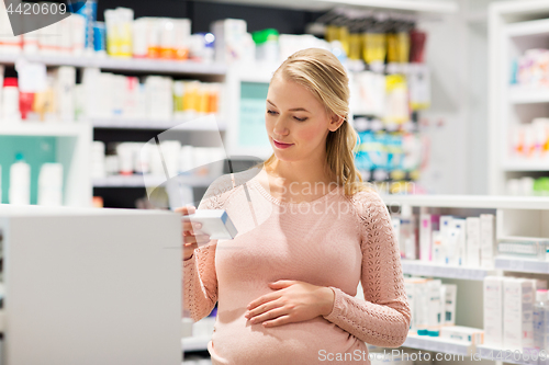 Image of happy pregnant woman with medication at pharmacy