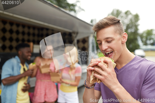 Image of happy man with hamburger and friends at food truck