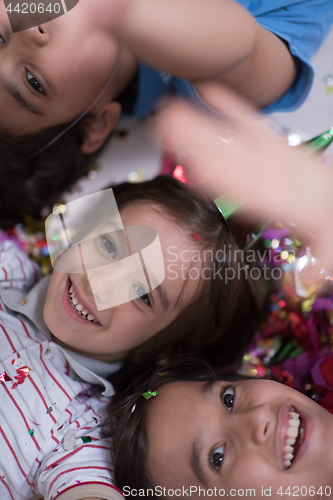 Image of kids  blowing confetti while lying on the floor