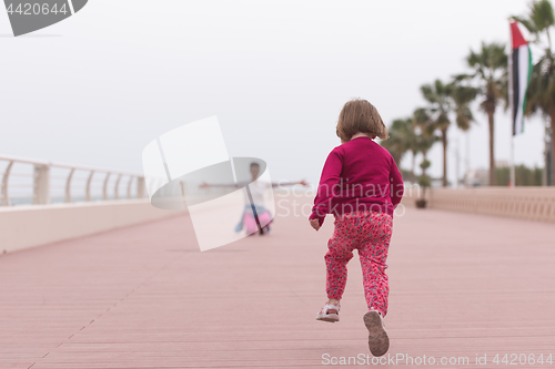 Image of mother and cute little girl on the promenade by the sea