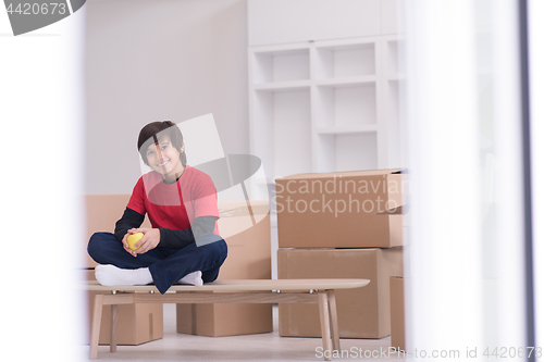 Image of boy sitting on the table with cardboard boxes around him