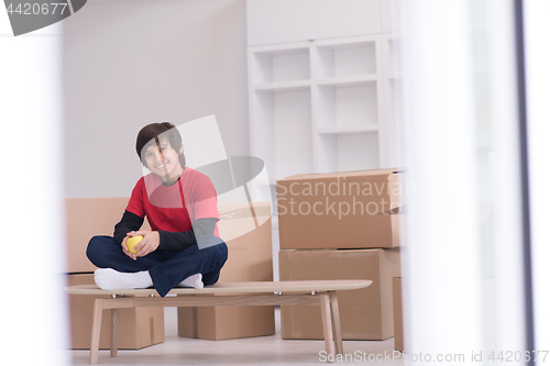 Image of boy sitting on the table with cardboard boxes around him