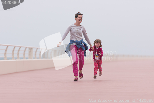 Image of mother and cute little girl on the promenade by the sea