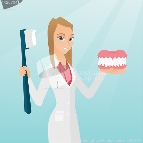 Image of Dentist with a dental jaw model and a toothbrush.