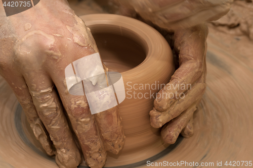 Image of Women hands in process of making clay bowl on pottery wheel