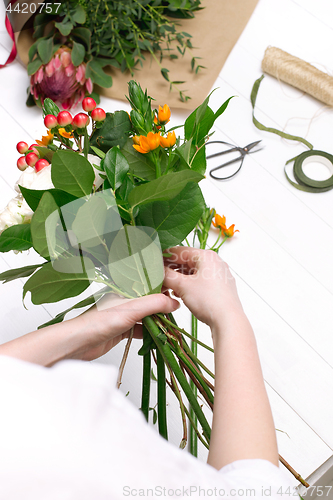 Image of Female florist making beautiful bouquet at flower shop