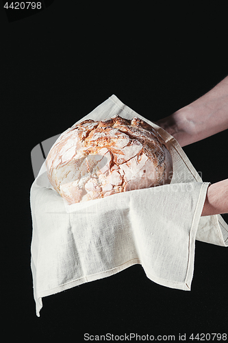 Image of Closeup of male hands put fresh bread on black background with copy space for your text