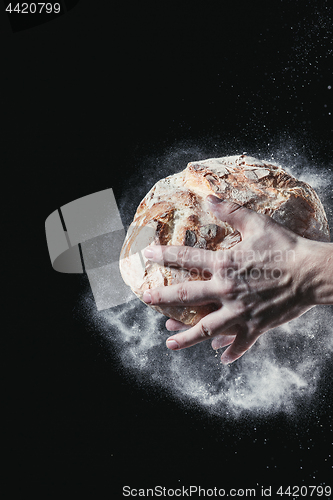 Image of Closeup of male hands put fresh bread on black background with copy space for your text