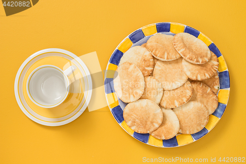 Image of Teacup and plate with pita bread on yellow background