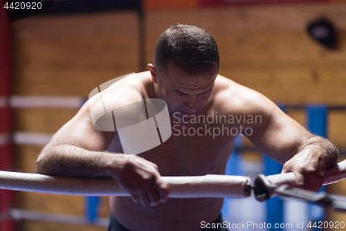 Image of kick boxer resting on the ropes in the corner