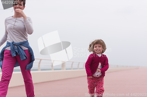 Image of mother and cute little girl on the promenade by the sea