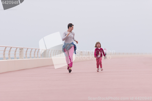 Image of mother and cute little girl on the promenade by the sea