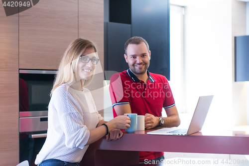 Image of couple drinking coffee and using laptop at home