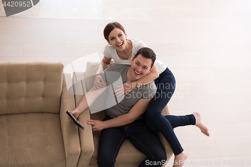 Image of couple relaxing at  home with tablet computers