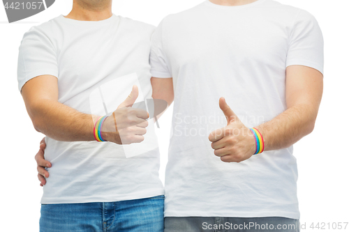 Image of gay couple with rainbow wristbands shows thumbs up