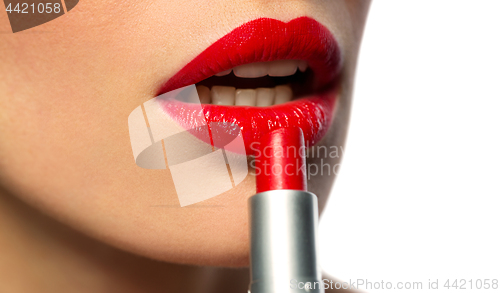 Image of close up of woman applying red lipstick to lips