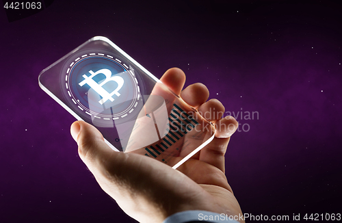 Image of hand with smartphone and bitcoin hologram