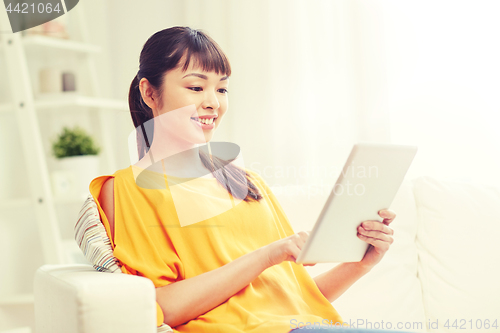 Image of happy young asian woman with tablet pc at home