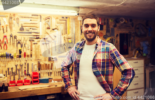 Image of happy young workman in checkered shirt at workshop