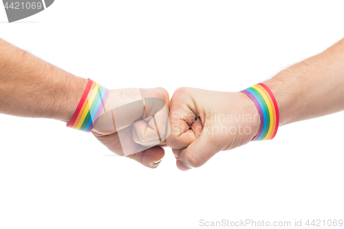 Image of hands with gay pride wristbands make fist bump