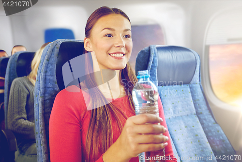 Image of happy young woman with water bottle in plane