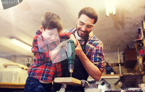 Image of father and son with drill working at workshop